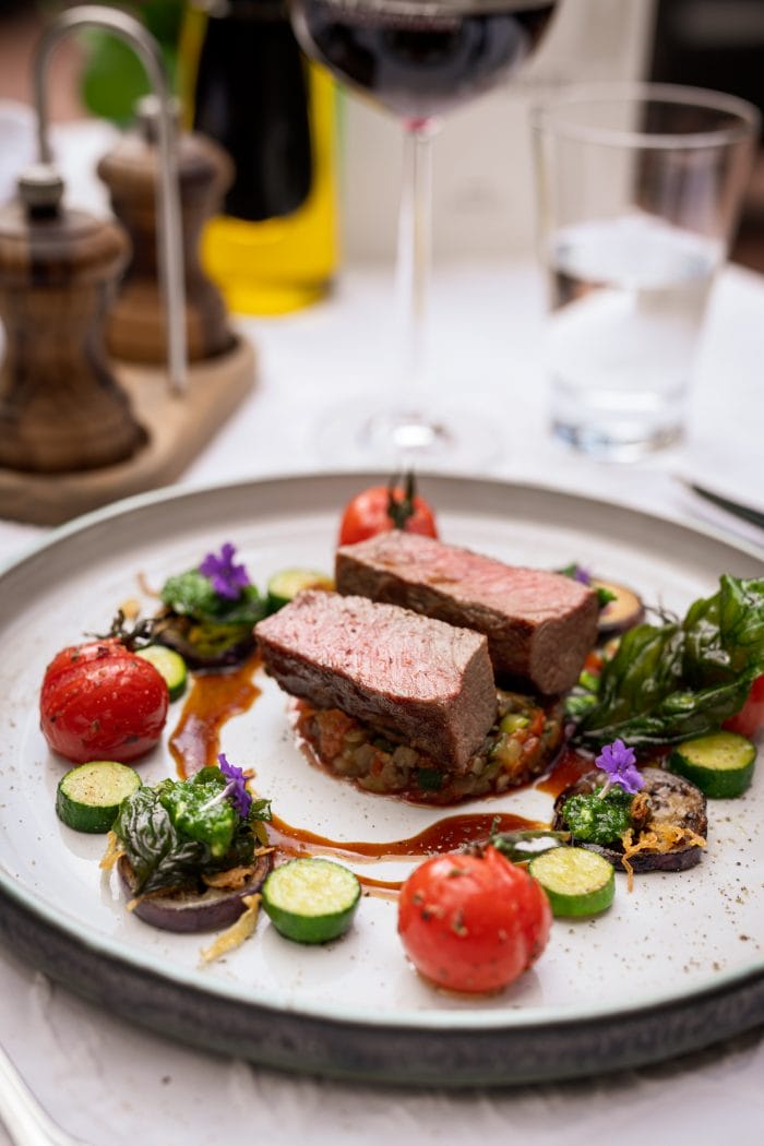Restauranttisch mit gechmorten Heidschnucken-Rücken und mediterranen Gemüse
