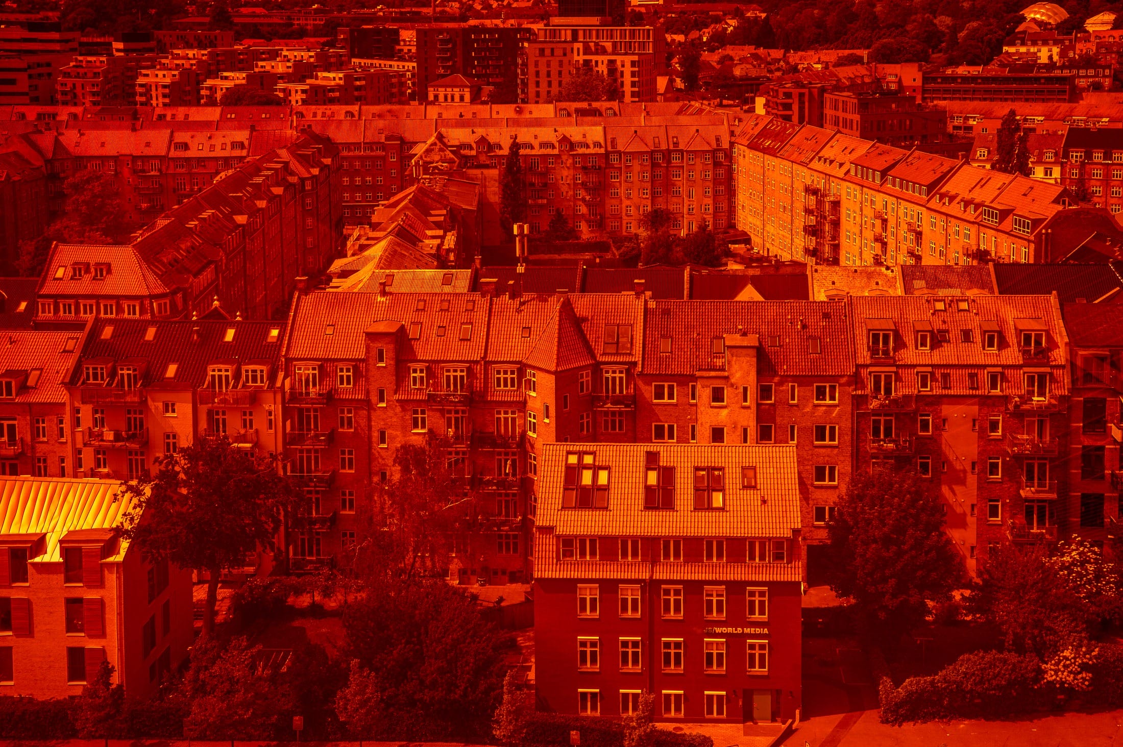 Alte Quartier-Häuser im dänischen Aarhus, durch den Panorama Walk des ARoS-Museums fotografiert, in rötliches Licht gesetzt.