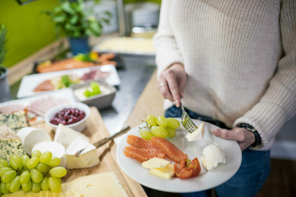 Aussagekräftige Fotos für Ihr Hotel-Unternehmen. Hotelgast stellt sich einen Frühstücksteller am Frühstücksbuffet zusammen.