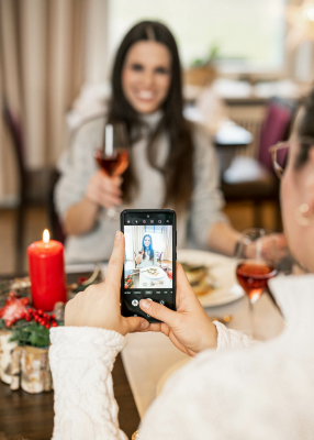 Aussagekräftige Fotos für Ihr Hotel-Unternehmen. Restaurantsituation in der ein Gast von einem anderen Gast ein Handyfoto an einem gedeckten Tisch macht.