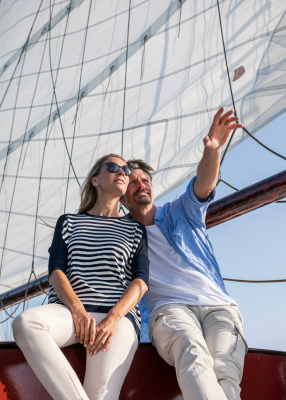 Tourismusfotos, ein Paar auf Segeltour, er zeigt in die Ferne