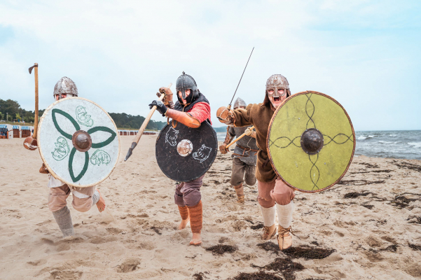 Eine Gruppe Wikinger läuft während eines Wikinger-Events auf den Betrachter des Tourismusfotos zu.