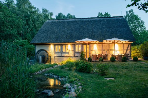kleine Mühlenbar in der Abendstimmung altes saniertes Mühlengebäude mit kleinem Bach, in dem sich die Bar und ein Partyraum befindet im Abendlicht