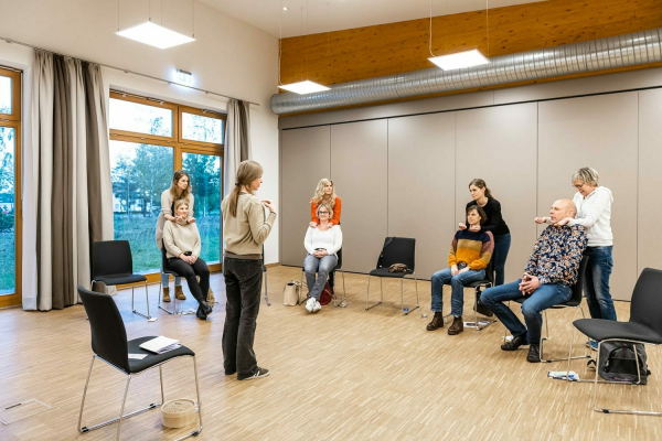 In einem Seminarraum hat sich einen Gruppe von Seminarteilnehmern versammelt um gemeinsam Übungen durchzuführen.