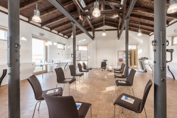 Eventraum im Eventcamp Reinsehlen - Lüneburger-Heide Der moderne Eventraum befindet sich in einem alten Pferdestall. Die alte Industriearchitektur läßt ihren Charme spielen. Die Stühle sind in einem Stuhlkreis angeordnet.