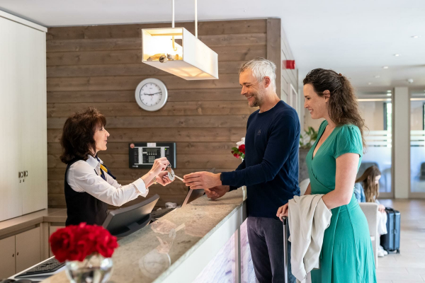 Hotelgäste bei der Schlüsselübergabe in der Hotellobby.