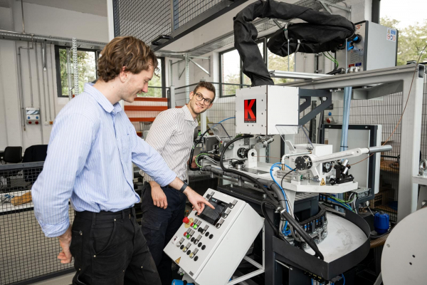 zwei Mitarbeiter der Leuphana Universität bedienen eine Maschine in der Maschinenhalle