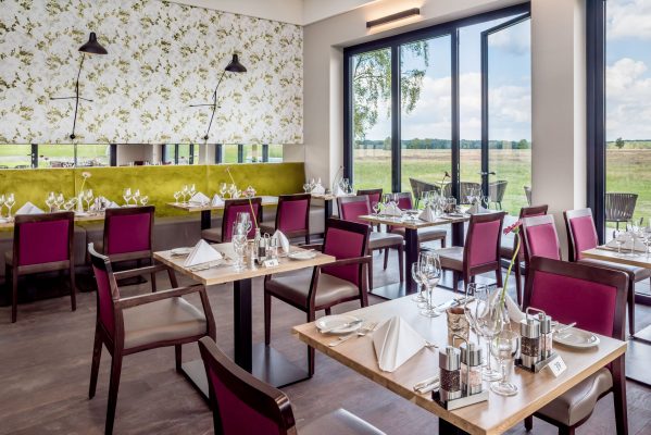 Restaurant Hotel Camp-Reinsehlen Lüneburger-Heide Hotelfoto vom Restaurant des Hotelcamps Reinsehlen mit voll eingedeckten Tischen. Aus dem Restaurant kann der Restaurantgast nach draußen in das Naturschutzgebiet schauen.