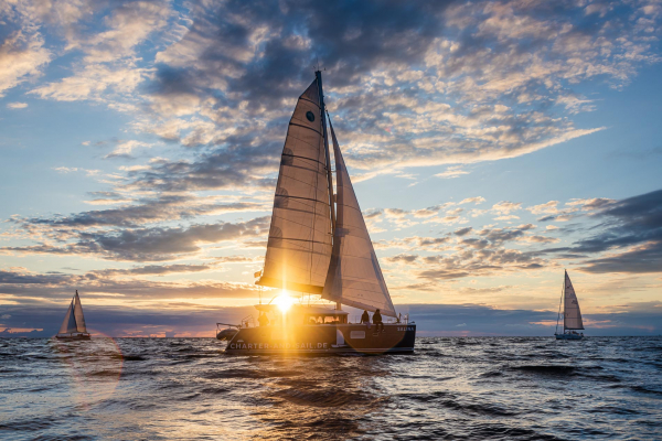 Ein Segel-Katamaran bei Sonnenuntergang im Gegenlicht auf der Ostsee