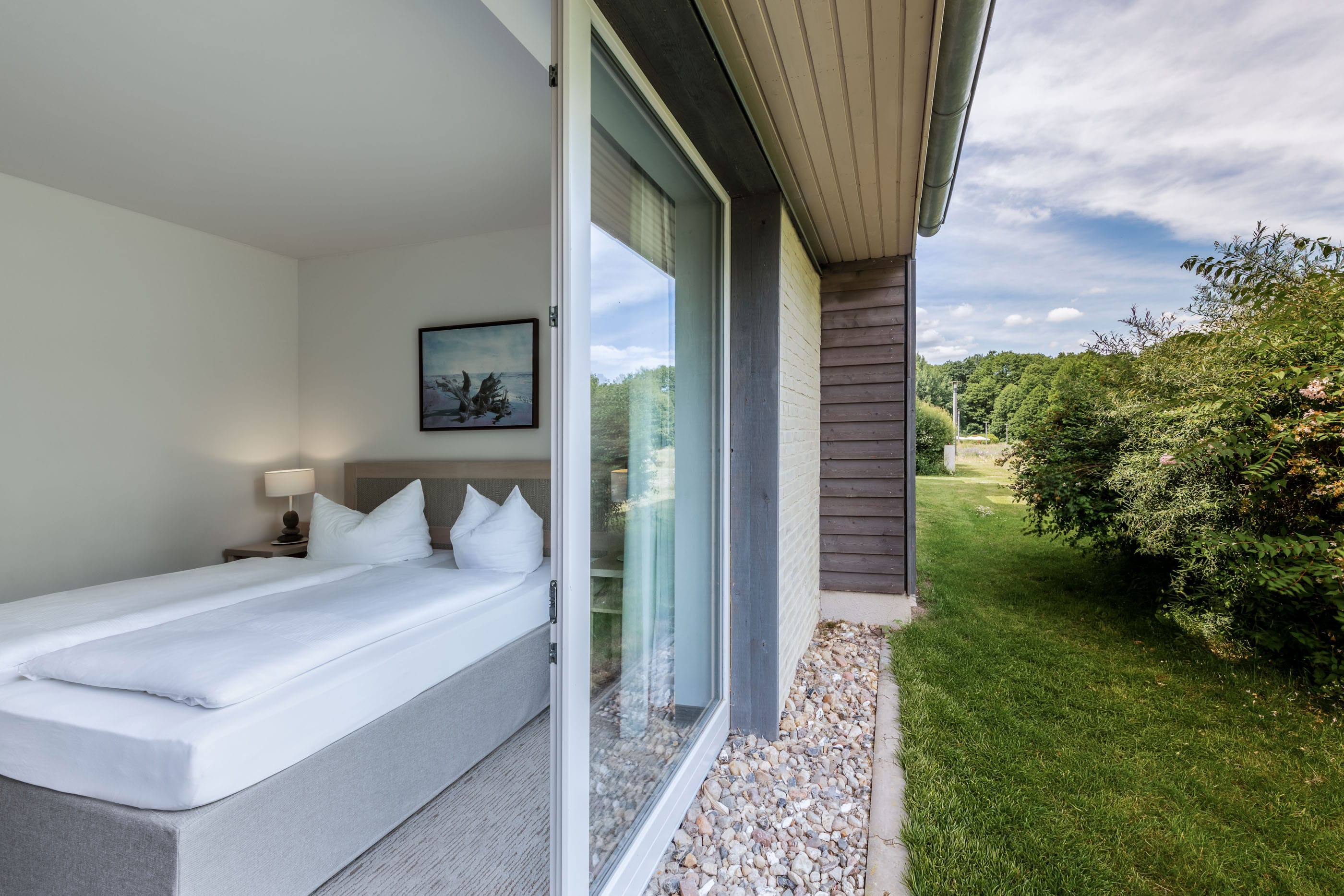 Hotelfoto von einem Hotelzimmer mit Doppelbett und Ausblick in den grünen Garten
