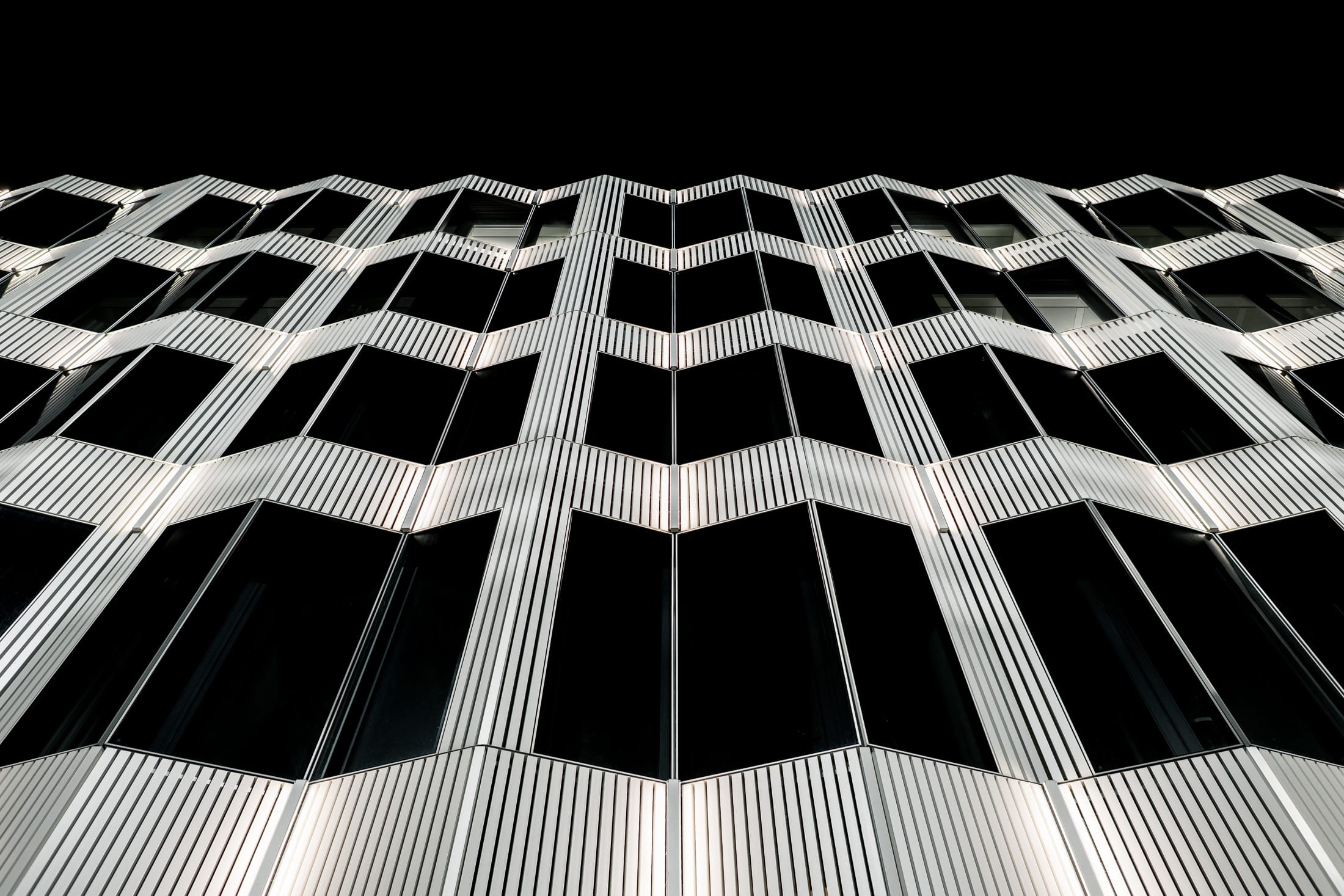 helle, fast weiße moderne Berliner Architekturfassade im Kontrast zur Dunkelheit fotografiert.