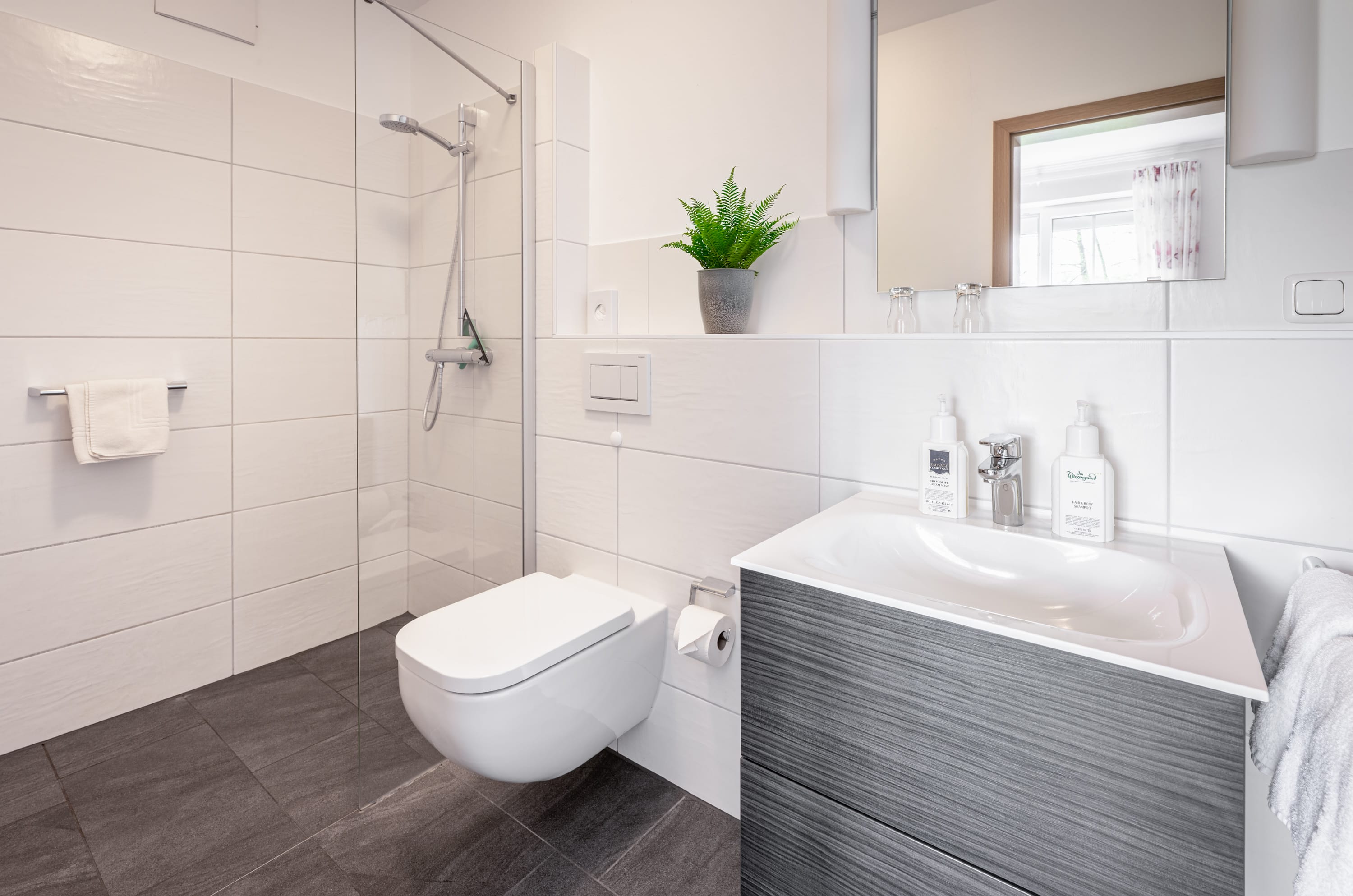professionelle Hotelfotos von modernen Hotel-Badezimmern - in hellen Tönen mit Waschtisch, Toilette und offener Dusche