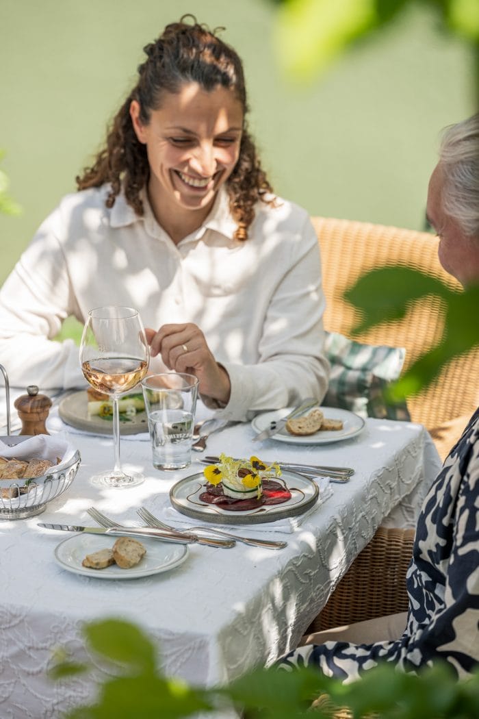 zwei Frauen sitzen gutgelaunt an einem Restauranttisch und freuen sich über das leckere angerichtete Essen auf dem Tisch
